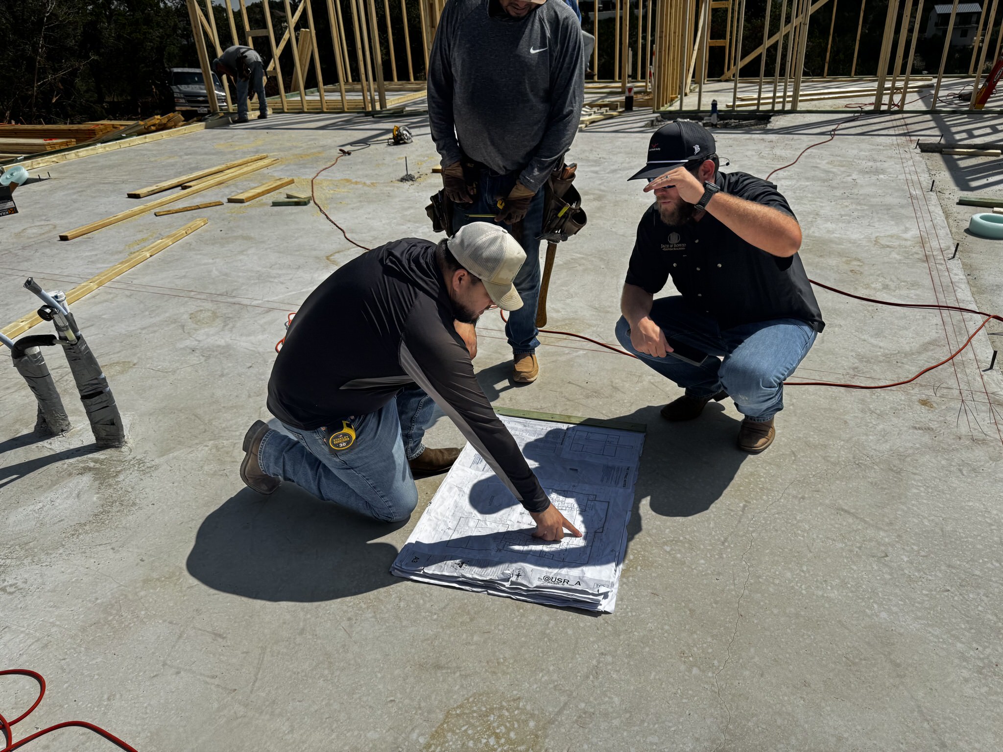 Builder reviewing site plans and permit documents at a construction site.
